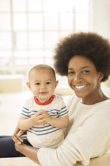 Mother holding baby boy on sofa at home — Stock Photo