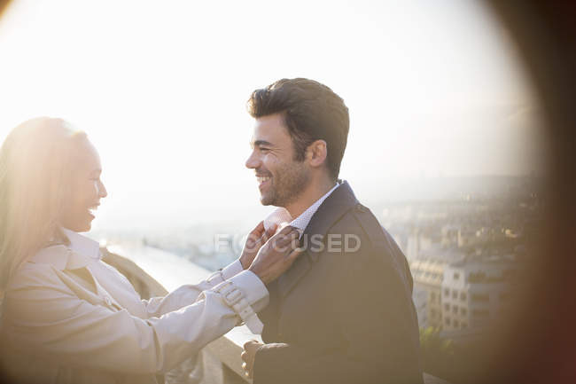 Woman holding boyfriend's collar on urban balcony — Stock Photo