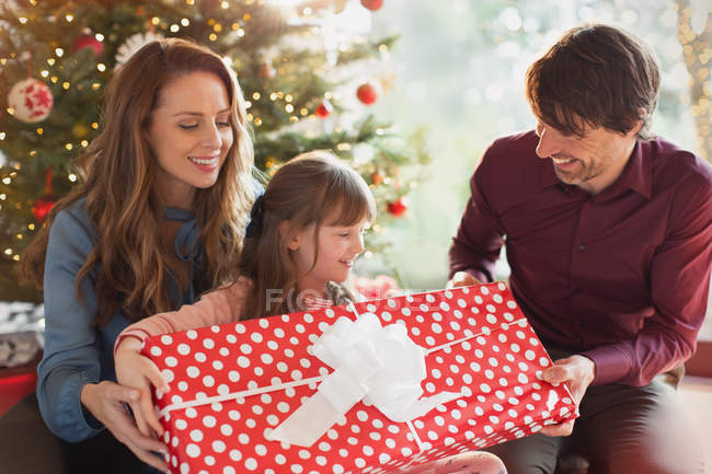 Genitori che fanno un grande regalo di Natale alla figlia davanti all'albero di Natale — Foto stock