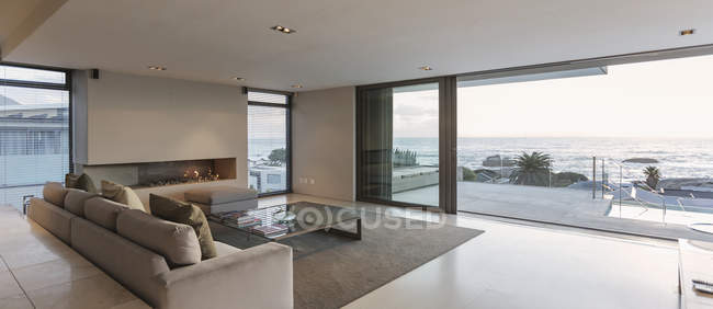 Moderna casa di lusso vetrina soggiorno con porte finestre aperte sull'oceano e patio — Foto stock