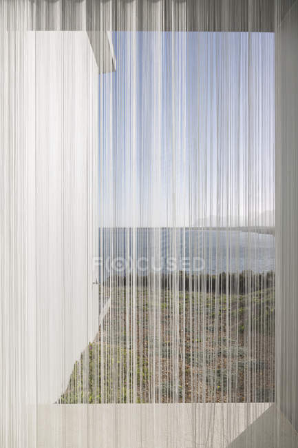 Gauze curtains in sunny, tranquil window with ocean view — Stock Photo