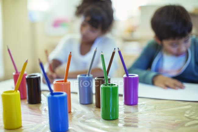 Colored pencils on desk in classroom — Stock Photo