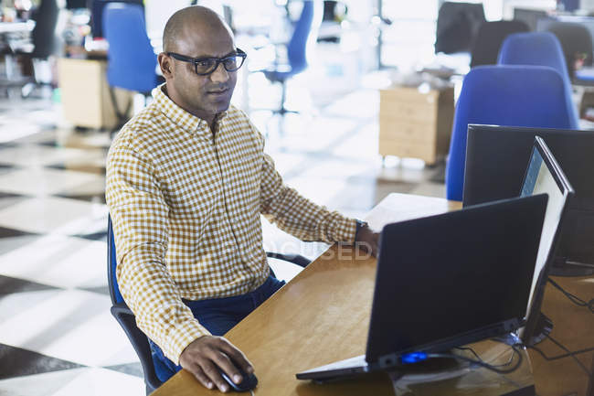 Бізнесмен, що працює на ноутбуці та комп'ютері в офісі — стокове фото