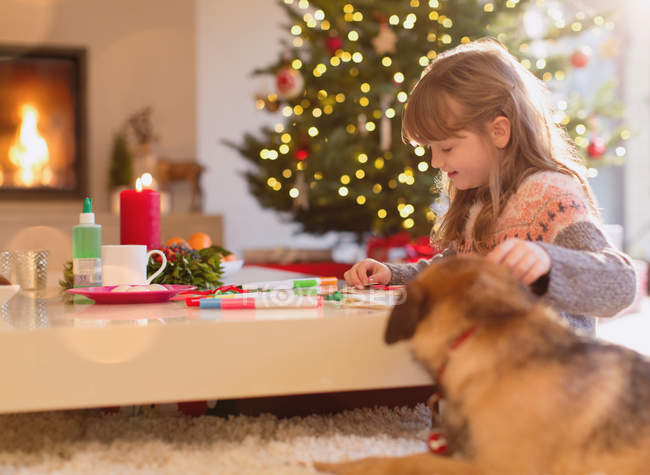 Cane guardando ragazza colorare con pennarelli nel soggiorno di Natale — Foto stock