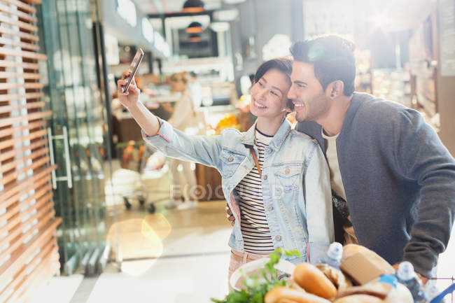 Giovane coppia prendendo selfie alimentari shopping nel mercato — Foto stock
