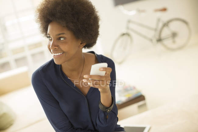 Mujer usando el teléfono celular en la sala de estar en casa - foto de stock