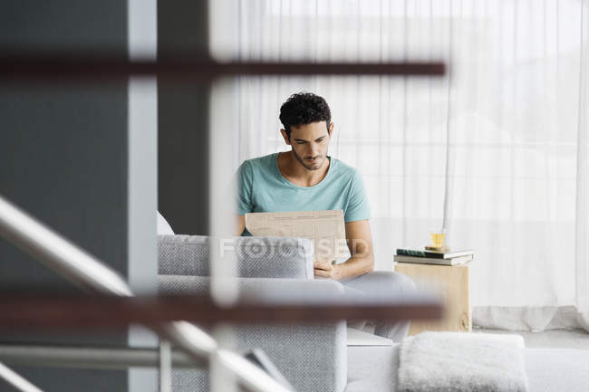 Hombre leyendo el periódico en la sala de estar en casa - foto de stock