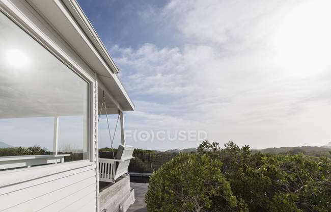 Sunny casa bianca vetrina esterna circondata da alberi verdi — Foto stock