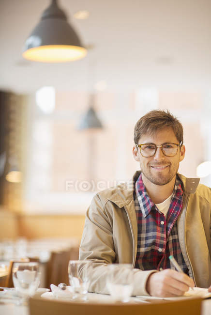 Счастливый молодой человек делает заметки в кафе — стоковое фото
