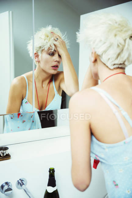 Mulher de ressaca examinando-se no espelho — Fotografia de Stock