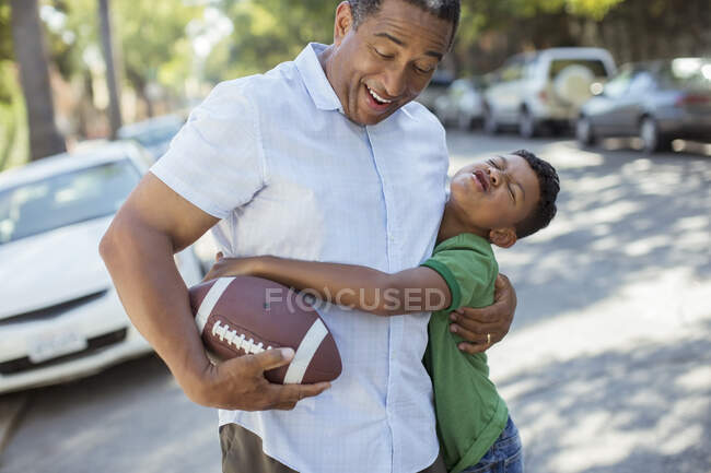 Grandson tackling grandfather with football — Stock Photo