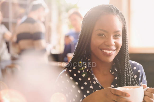 Портрет улыбающейся африканки, пьющей капучино в кафе — стоковое фото
