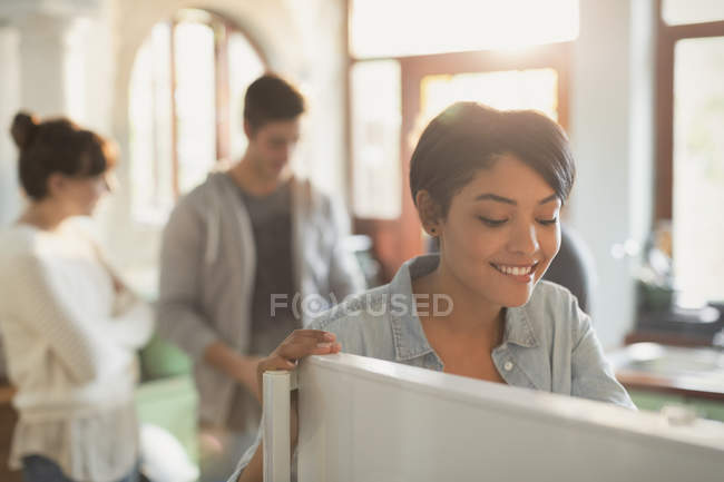 Smiling young woman looking into refrigerator in kitchen — Stock Photo