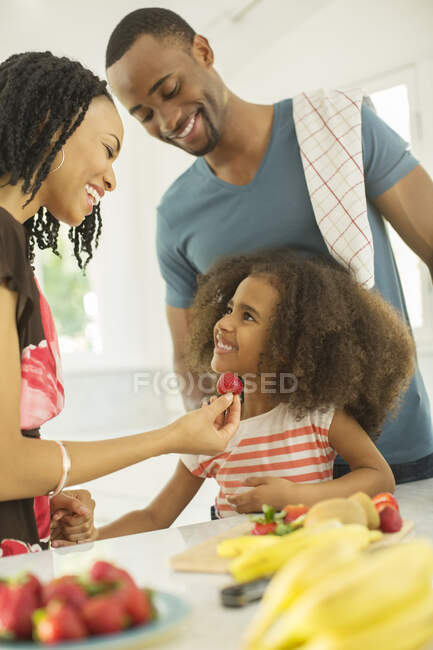 Счастливая семья ест клубнику — стоковое фото