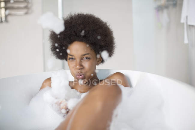 Женщина играет с пузырьками в ванной дома — стоковое фото