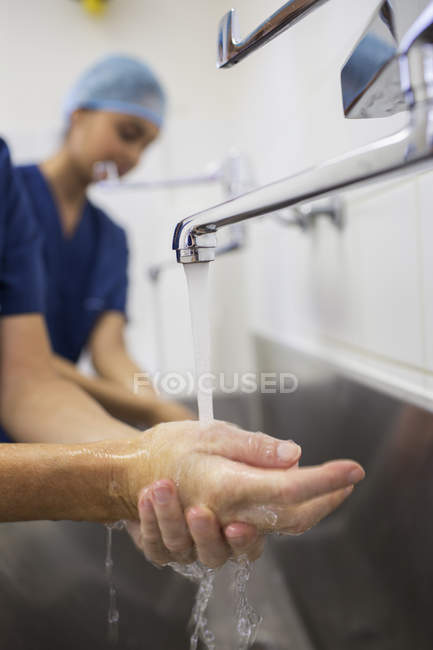 Primer plano de las manos del cirujano bajo el agua corriente - foto de stock