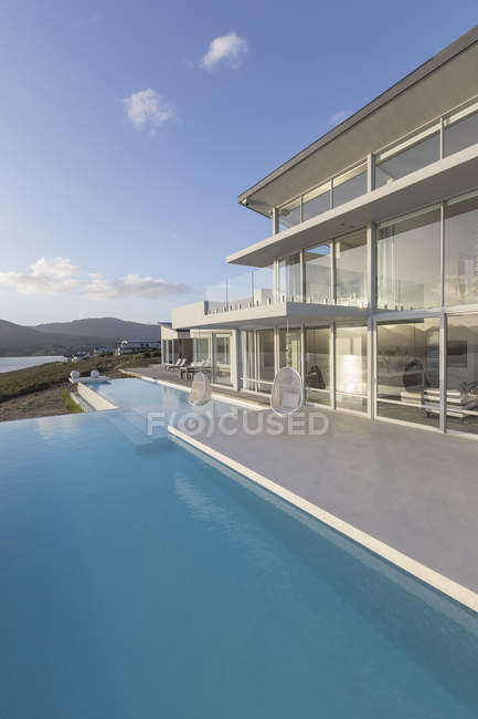 Tranquillo moderno lusso casa vetrina piscina a sfioro esterna — Foto stock