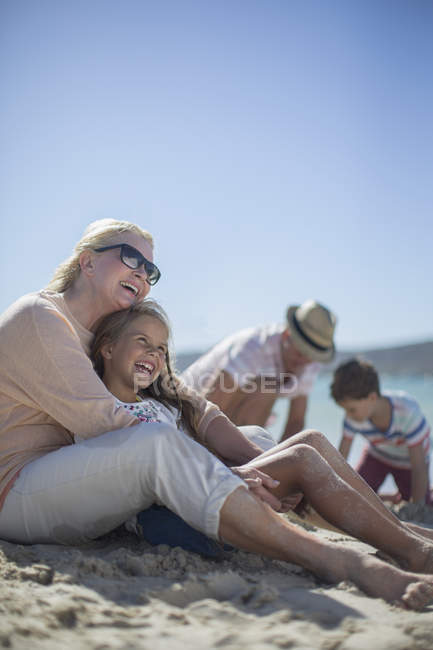 Família sentados juntos na praia arenosa — Fotografia de Stock