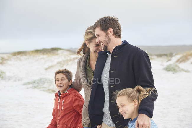 Familia feliz caminando en la playa de invierno - foto de stock