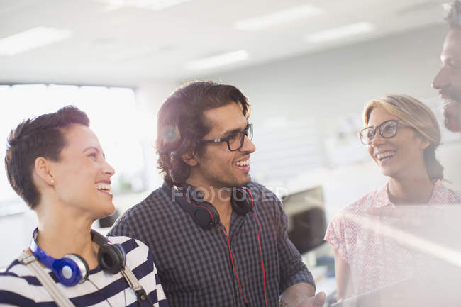 Sonriendo gente de negocios creativos hablando en la oficina - foto de stock