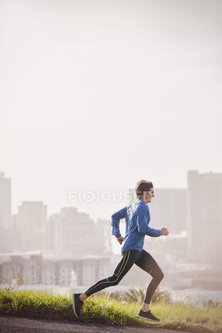 Чоловік біжить на сонячній міській вулиці — стокове фото