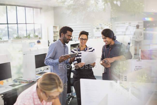 Creative business people with digital tablet discussing paperwork in office — Stock Photo