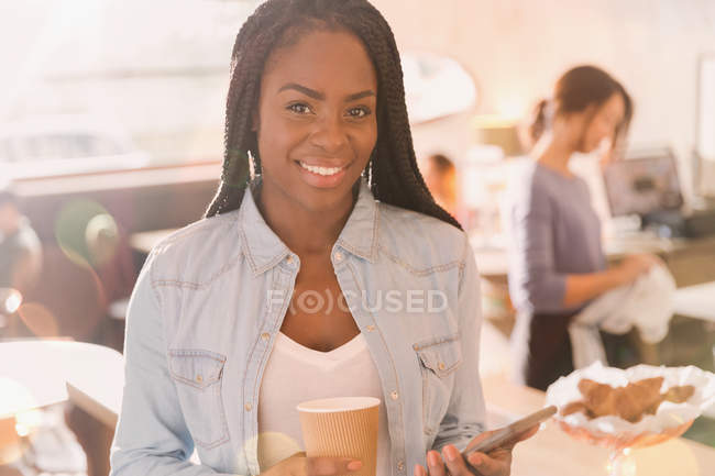 Retrato sorrindo mulher africana usando telefone celular e beber café no café — Fotografia de Stock