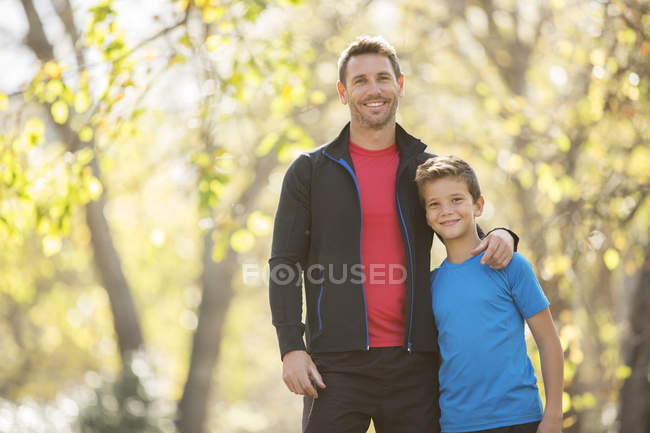Портрет улыбающихся отца и сына, обнимающихся на улице — стоковое фото
