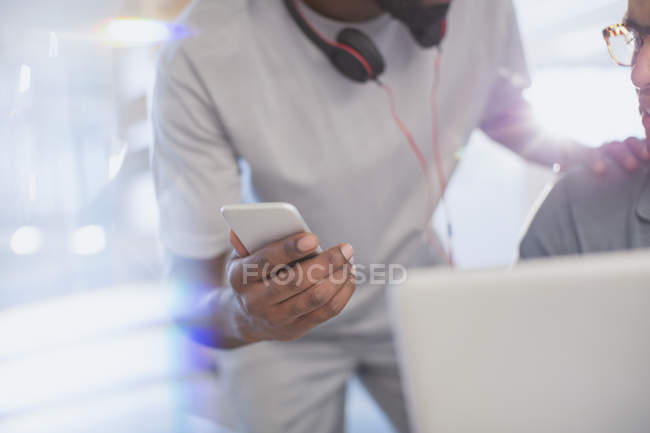 Close up creative businessman showing smart phone to colleague — Stock Photo
