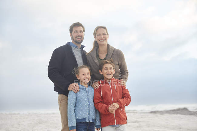 Retrato sonriente familia en la playa de invierno - foto de stock