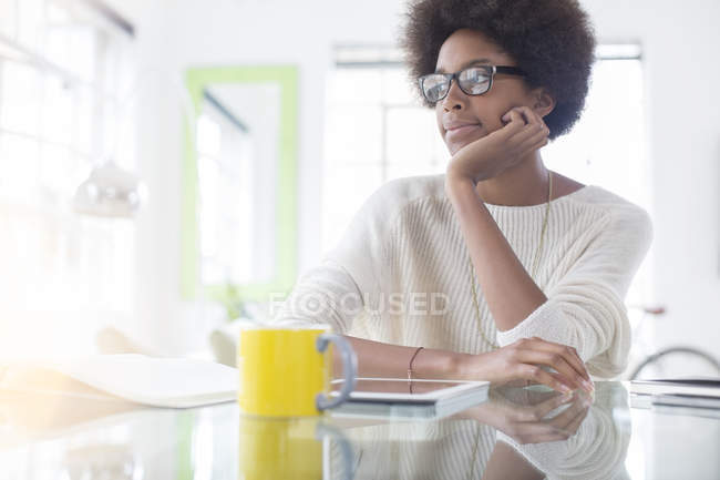 Nachdenkliche Frau nutzt digitales Tablet zu Hause am Tisch — Stockfoto