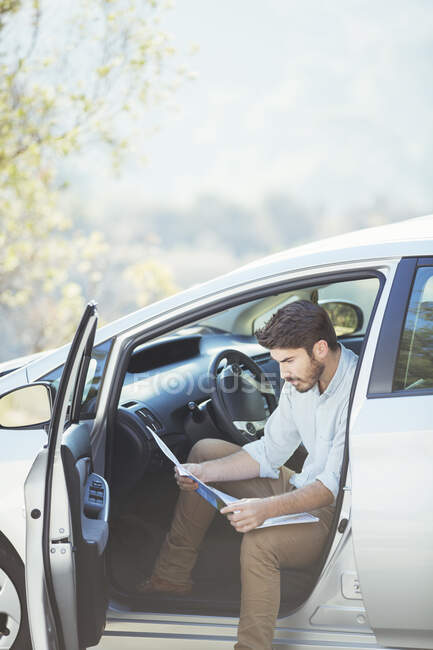 Man in car looking at map — Stock Photo