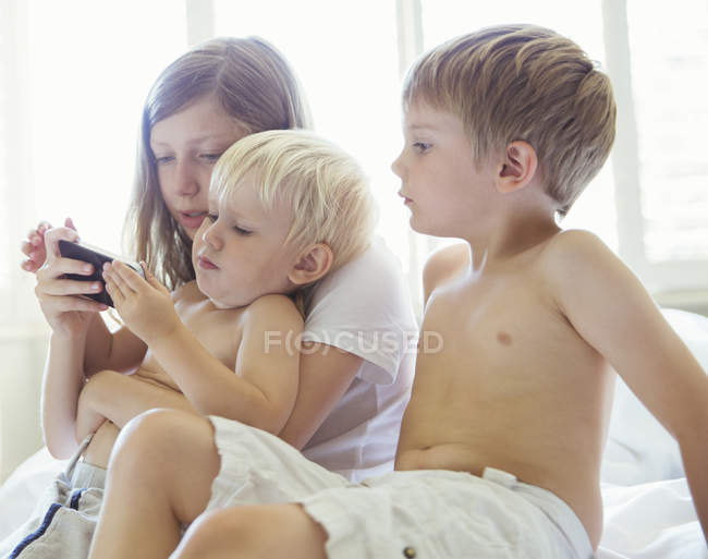 Дети используют мобильный телефон вместе — стоковое фото