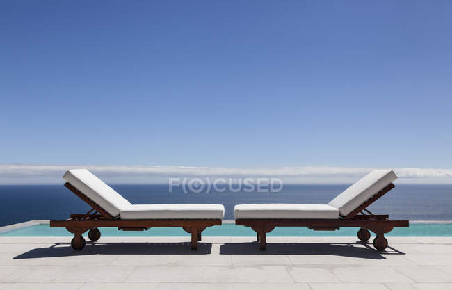 Стільці для відпочинку і нескінченний басейн з видом на океан — стокове фото