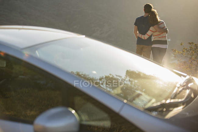 Пара обнимающихся возле машины у дороги — стоковое фото