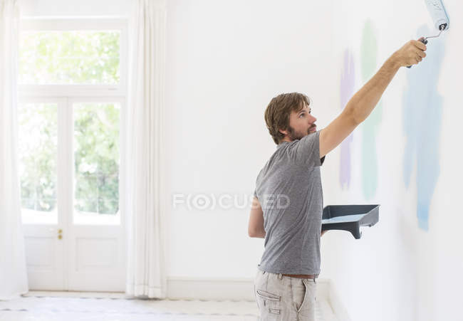 Mann bemalt Wand im Wohnraum — Stockfoto
