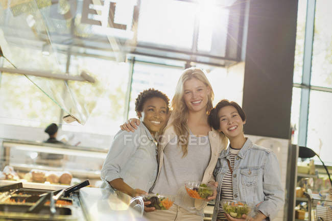 Retrato sonriente mujeres jóvenes disfrutando de bar de ensaladas en el mercado de comestibles - foto de stock