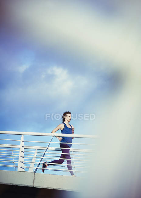 Une coureuse qui court sur une passerelle ensoleillée — Photo de stock