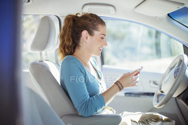 Mulher mensagens de texto com celular dentro do carro — Fotografia de Stock