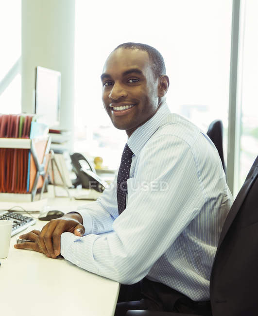 Geschäftsmann lächelt am Schreibtisch im Büro — Stockfoto