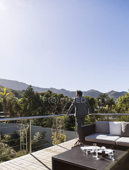 Pensive businessman on sunny balcony patio, looking at mountain view — Stock Photo
