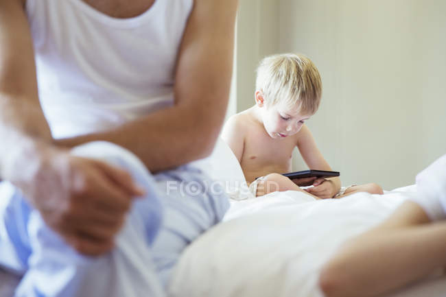 Мальчик с цифровым планшетом на кровати — стоковое фото