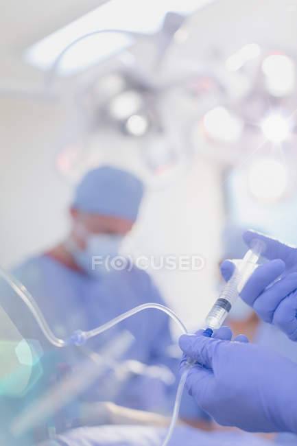 Close up anesthesiologist injecting anesthesia medicine into IV drip in operating room — Stock Photo
