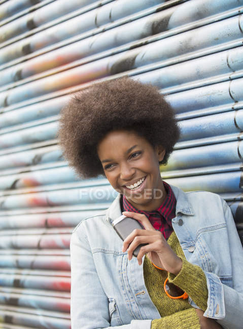 Frau mit Handy lächelt gegen Graffiti-Wand — Stockfoto