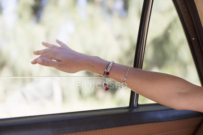 Woman feeling wind on her hand through car window — Stock Photo