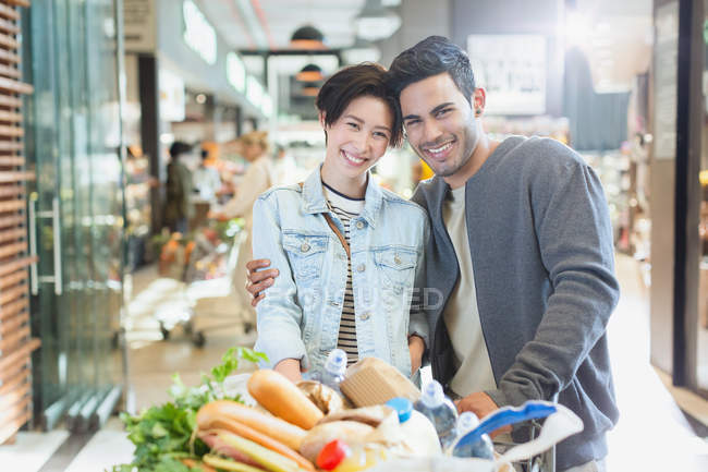 Retrato sonriente pareja joven compras en el mercado - foto de stock