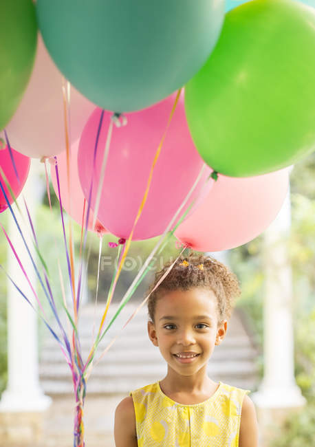Chica joven sosteniendo montón de globos - foto de stock