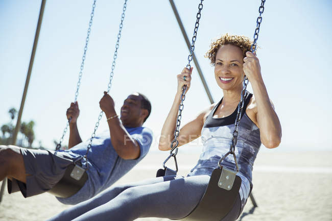 Couple on swings at beach — Stock Photo