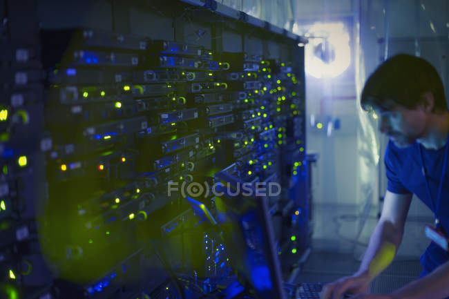 Technicien de salle de serveurs travaillant à l'ordinateur — Photo de stock