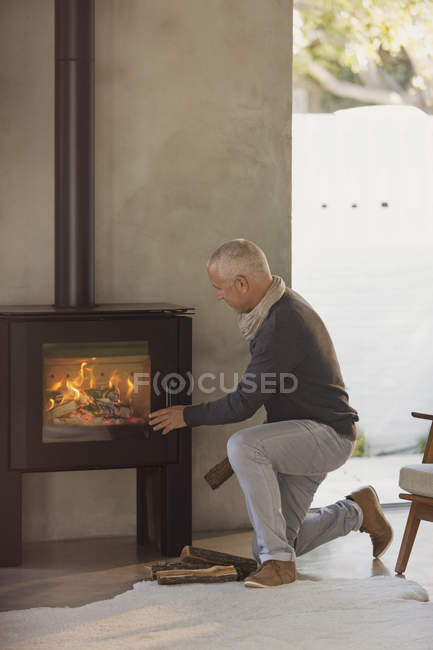 Man placing firewood in wood stove — Stock Photo